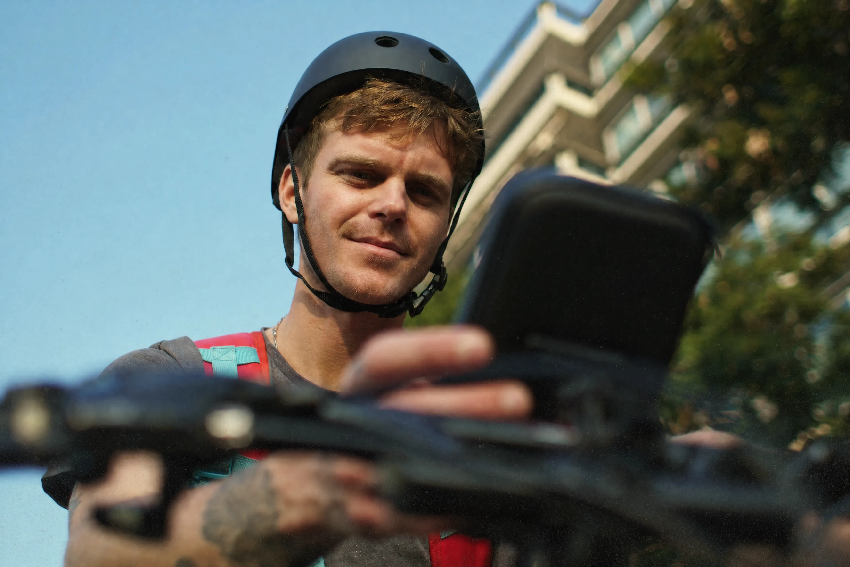 A delivery cyclist in a helmet checking the phone mounted on his handlebars
