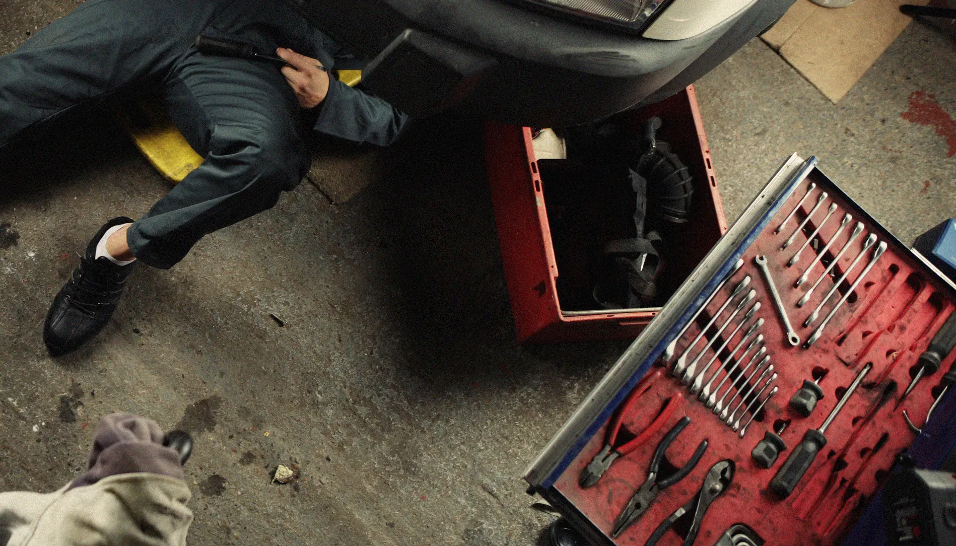 Overhead view of a mechanic working under a car next to a tool chest