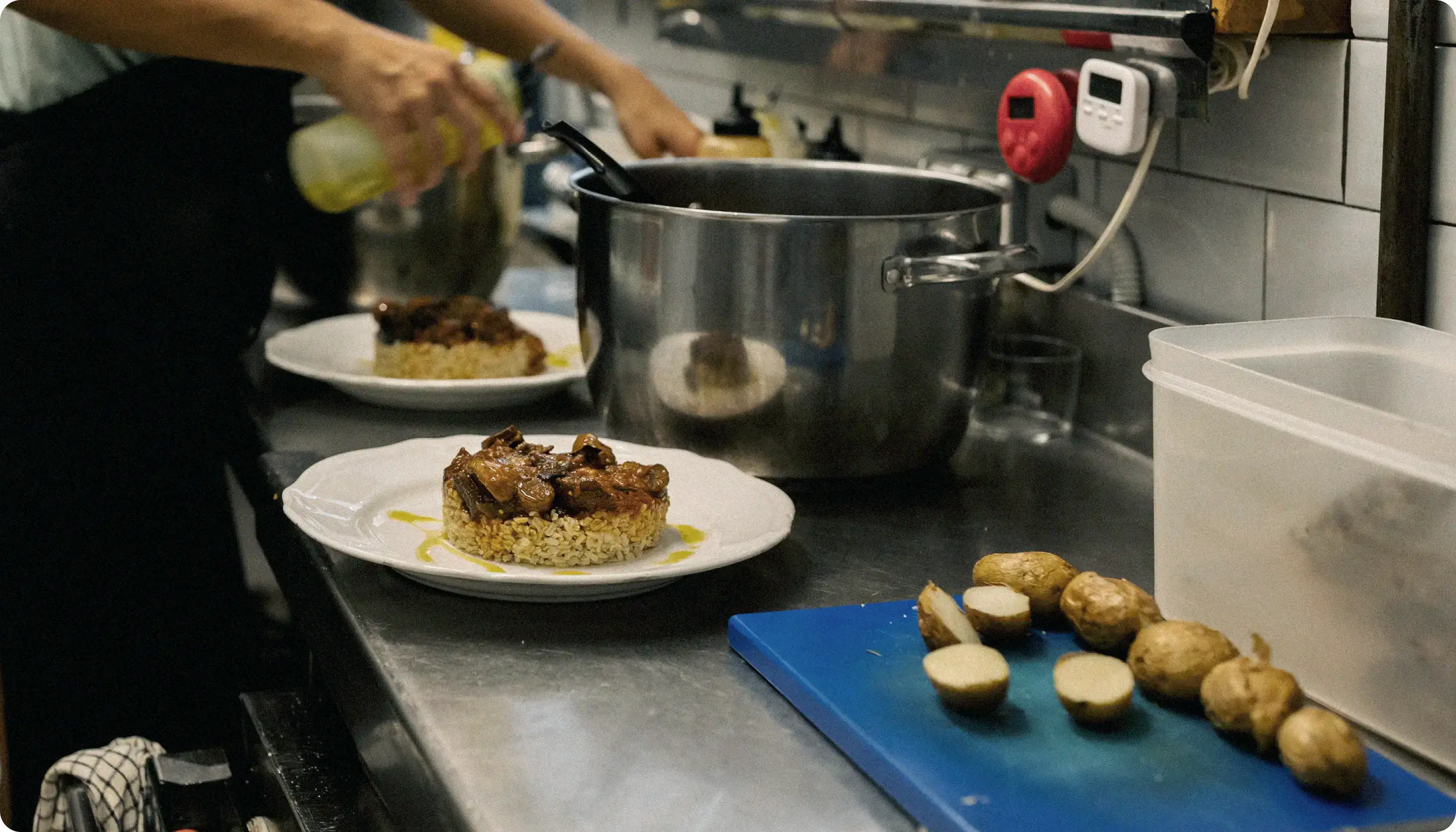 Chef plating dishes on a stainless steel counter in a restaurant kitchen